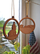 Last inn bildet i Galleri-visningsprogrammet, Sirkelformede utskjæringer som kan henges opp, med utskjeringer av prærielandsbyen og emigrantkyrkja